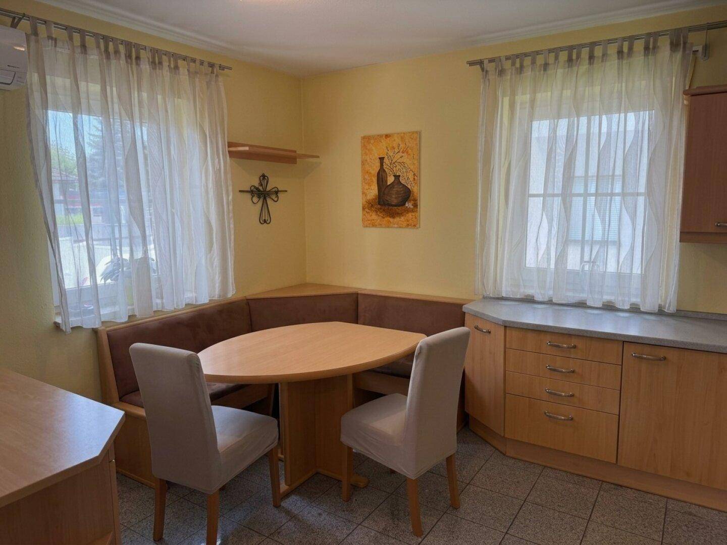Heller Essbereich mit Eckbank, Holztisch und zwei Fenstern, ideal für gemeinsame Mahlzeiten.