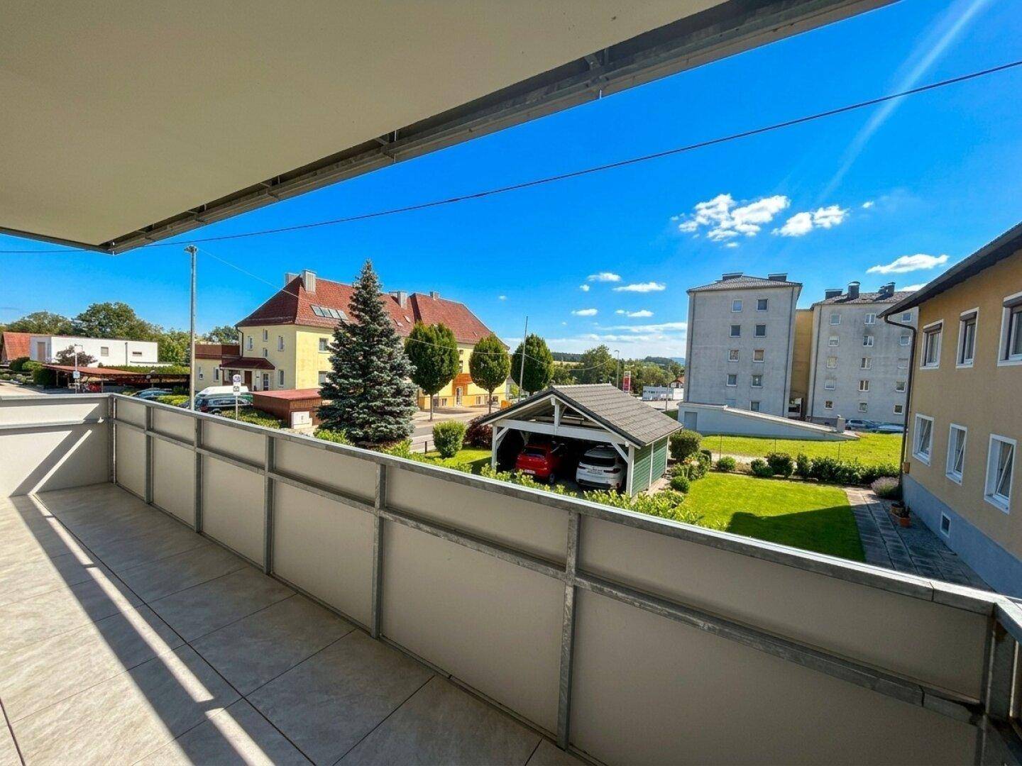 Geräumiger Balkon mit Fliesenboden und Blick auf die umliegende Wohngegend und Grünflächen.