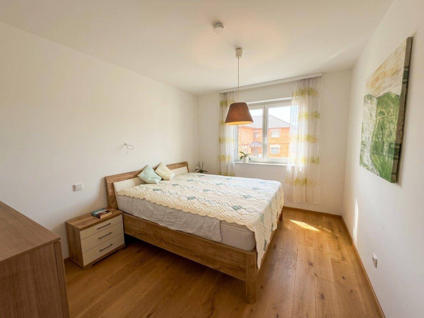 Gemütliches Schlafzimmer mit Doppelbett, Holzboden und einem Fenster mit Blick nach draußen.