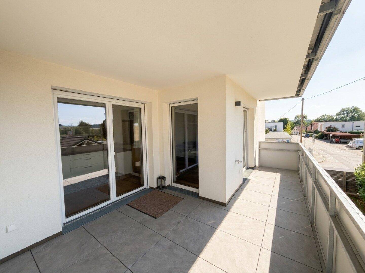 Geräumiger Balkon mit Fliesenboden, viel Sonnenlicht und einem weiten Blick auf die Umgebung.