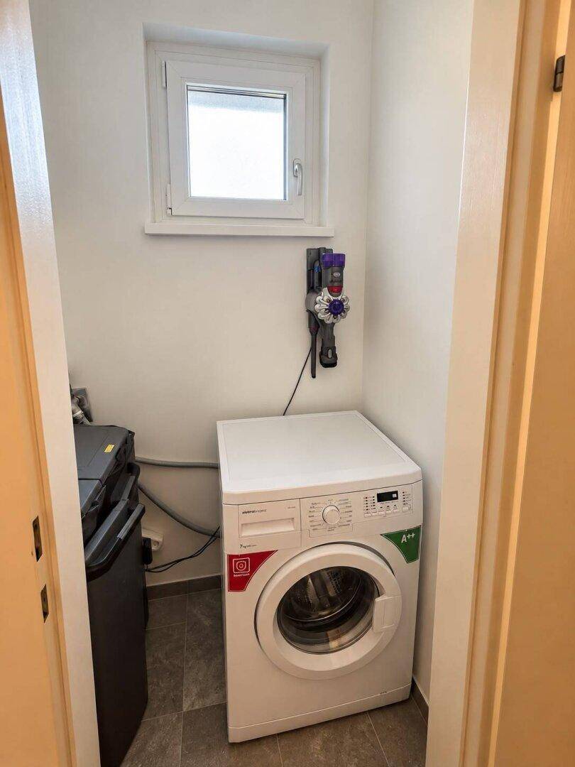 Praktischer Hauswirtschaftsraum mit Waschmaschine und Fenster für gute Belüftung.