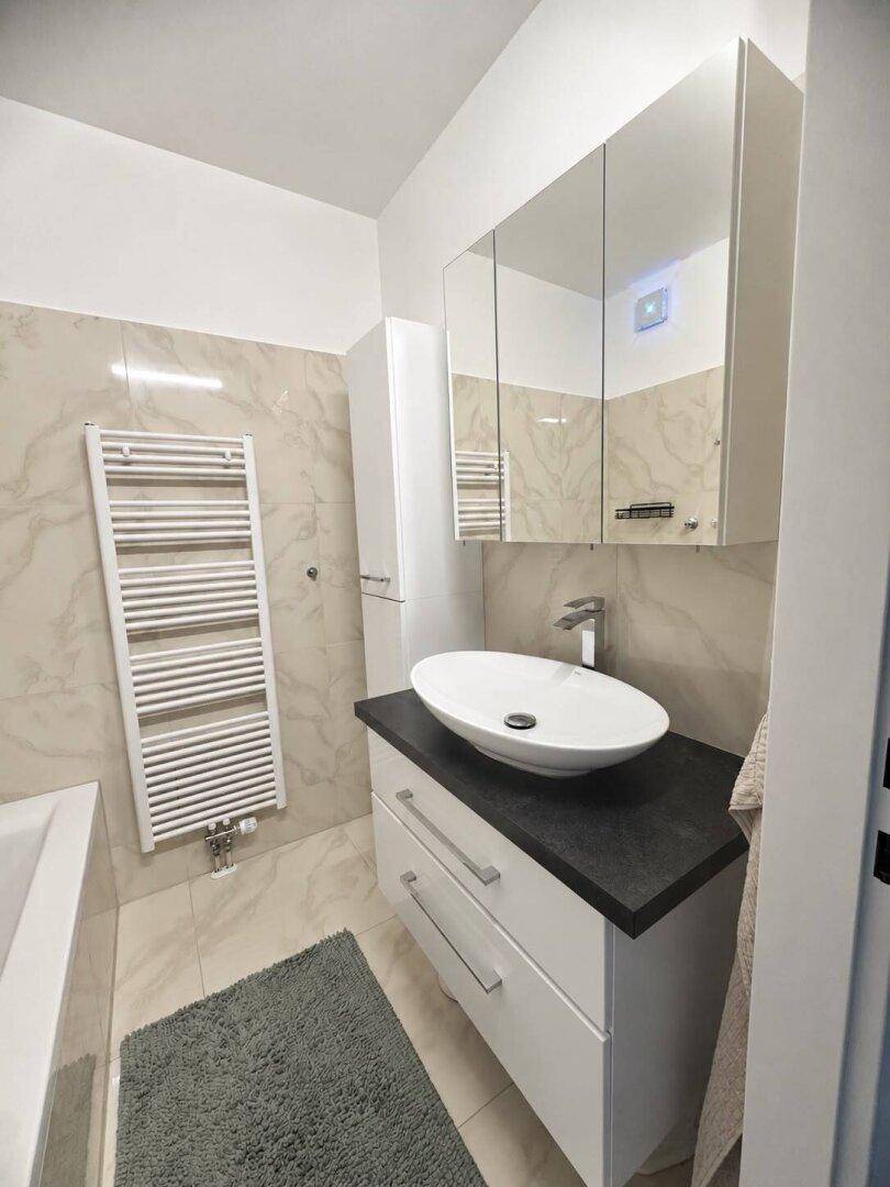 Modernes Badezimmer mit Aufsatzwaschbecken, Spiegelschrank und beheiztem Handtuchhalter.