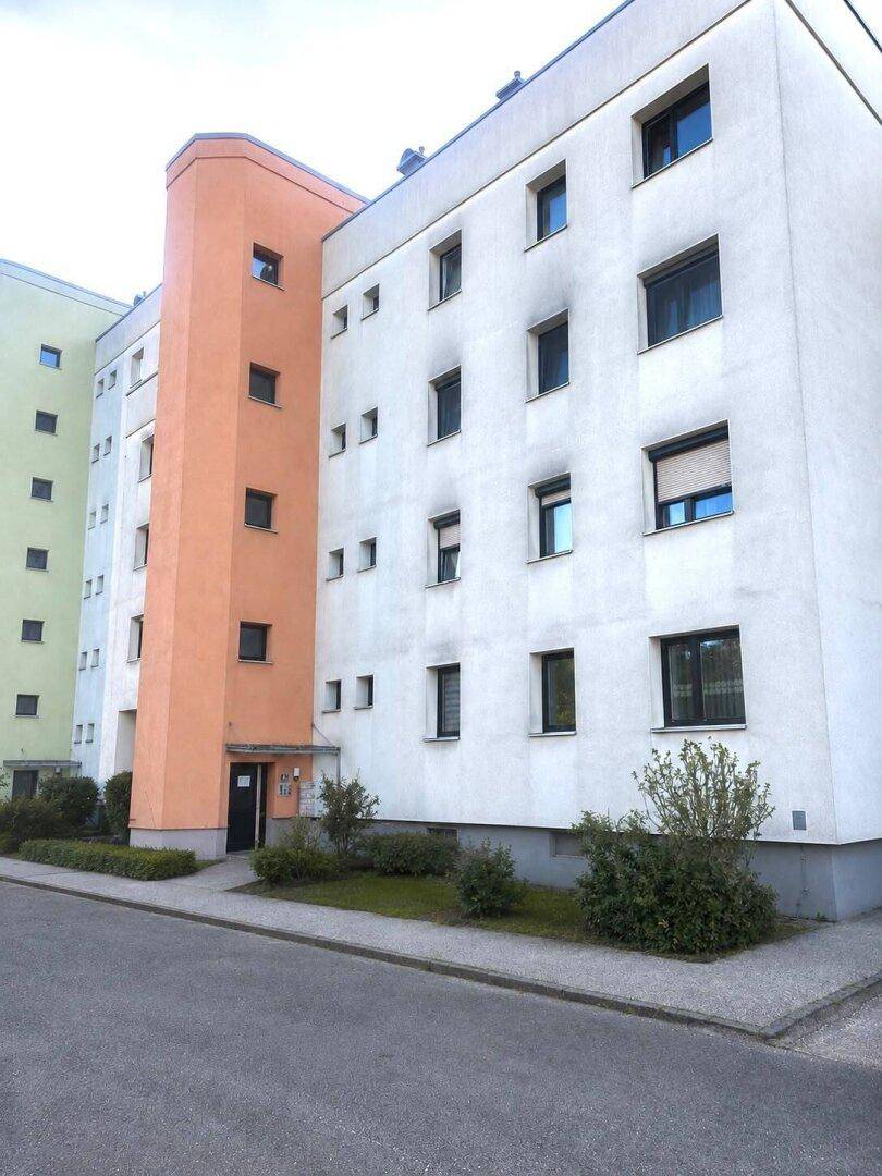 Mehrstöckiges Wohngebäude mit moderner Architektur und farbigen Fassadenakzenten.