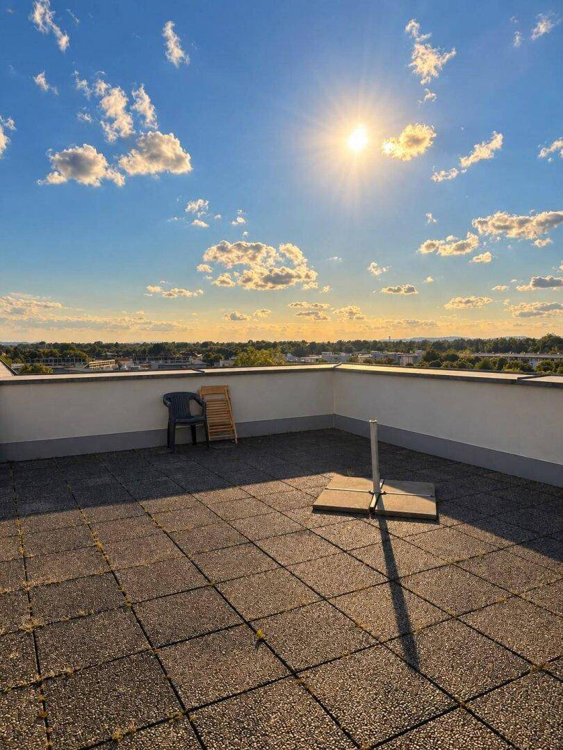 Geräumige Dachterrasse mit Weitblick über die Stadt unter strahlendem Sonnenschein.