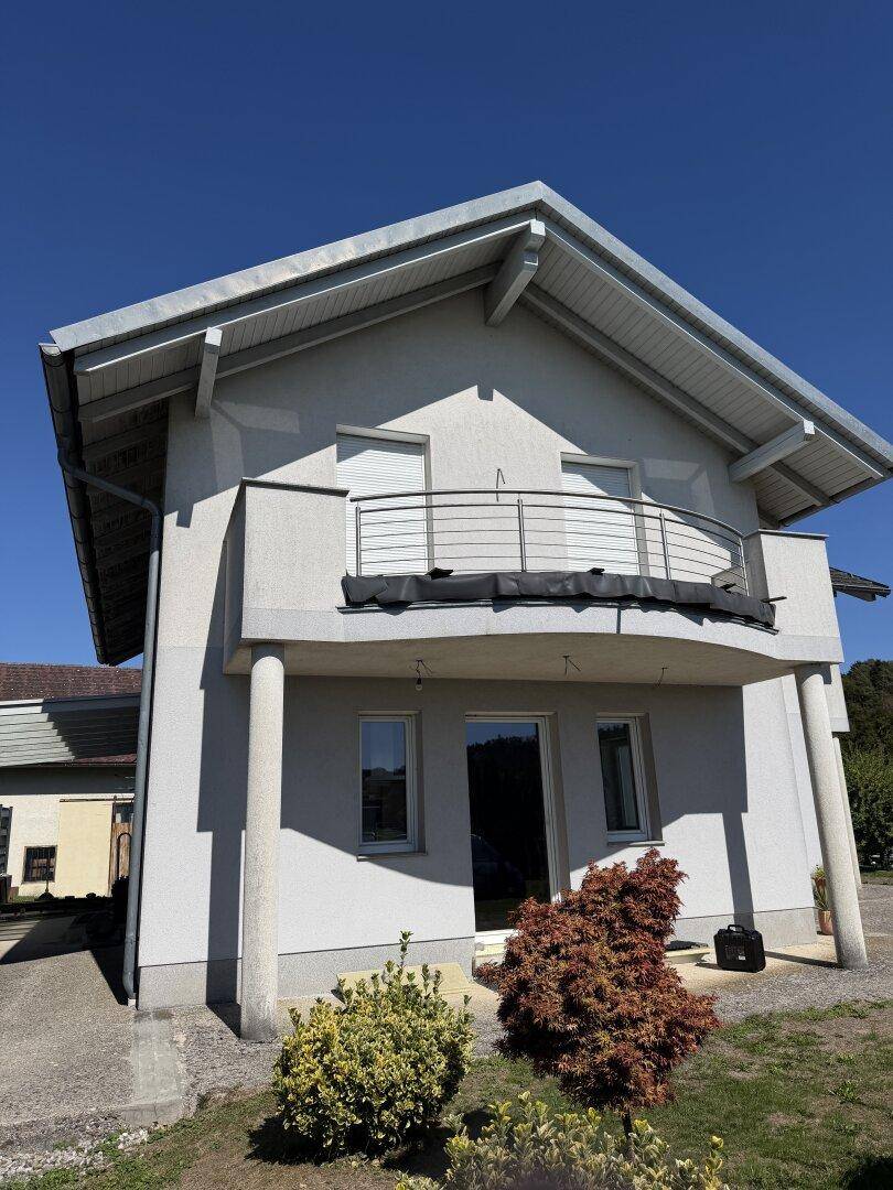 Vorderansicht des Hauses mit Balkon, Rollläden und gepflegter Bepflanzung im Vorgarten.