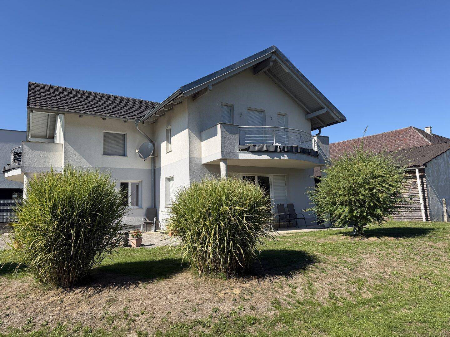 Rückansicht des Hauses mit kleiner Terrasse und Zugang zum weitläufigen Gartenbereich.