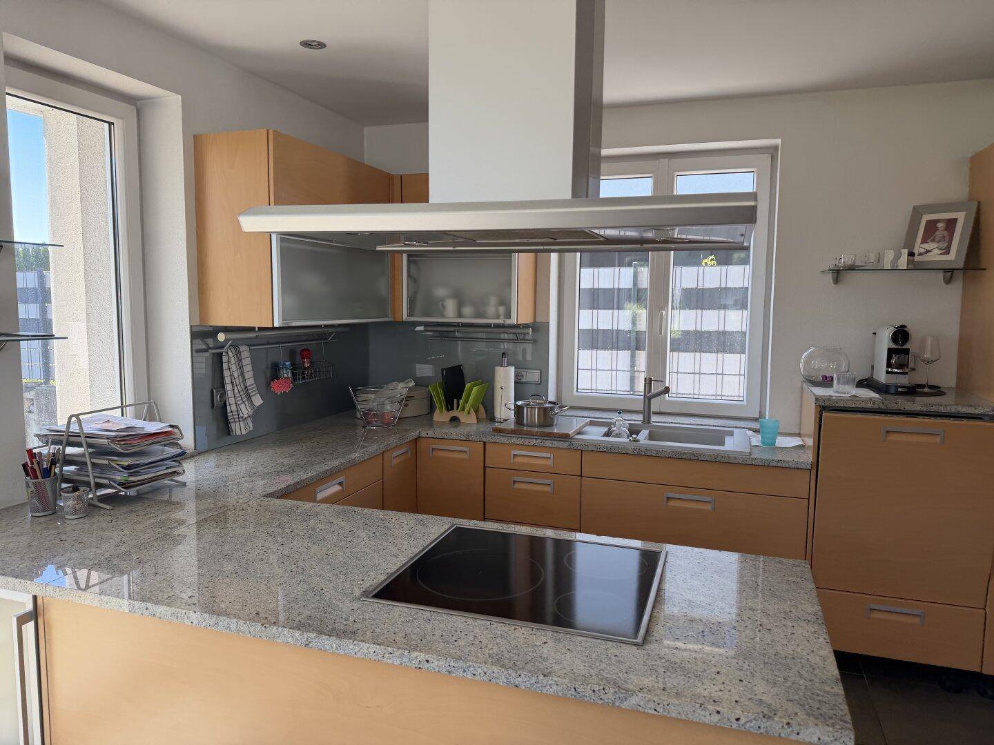 Moderne Küche mit hellen Holzfronten, Granitarbeitsplatten und Induktionskochfeld.