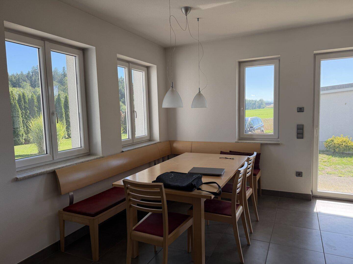 Heller Essbereich mit Holztisch und Eckbank, bietet weite Ausblicke auf die Landschaft.