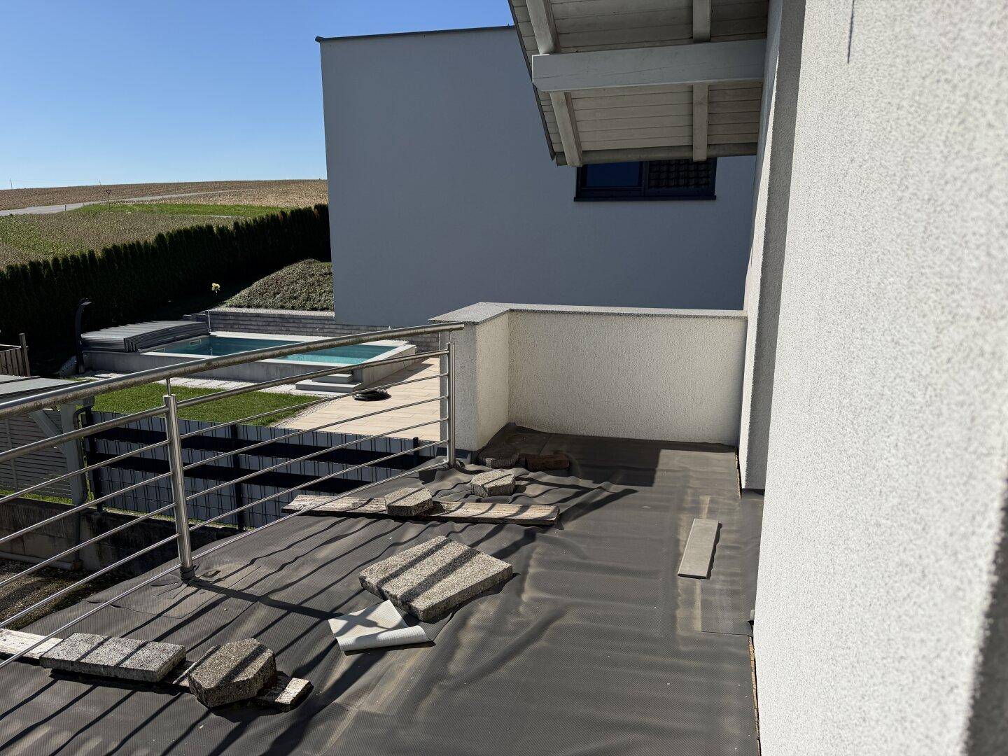 Balkon im Bauzustand mit Blick auf einen Pool und die umliegende Landschaft.