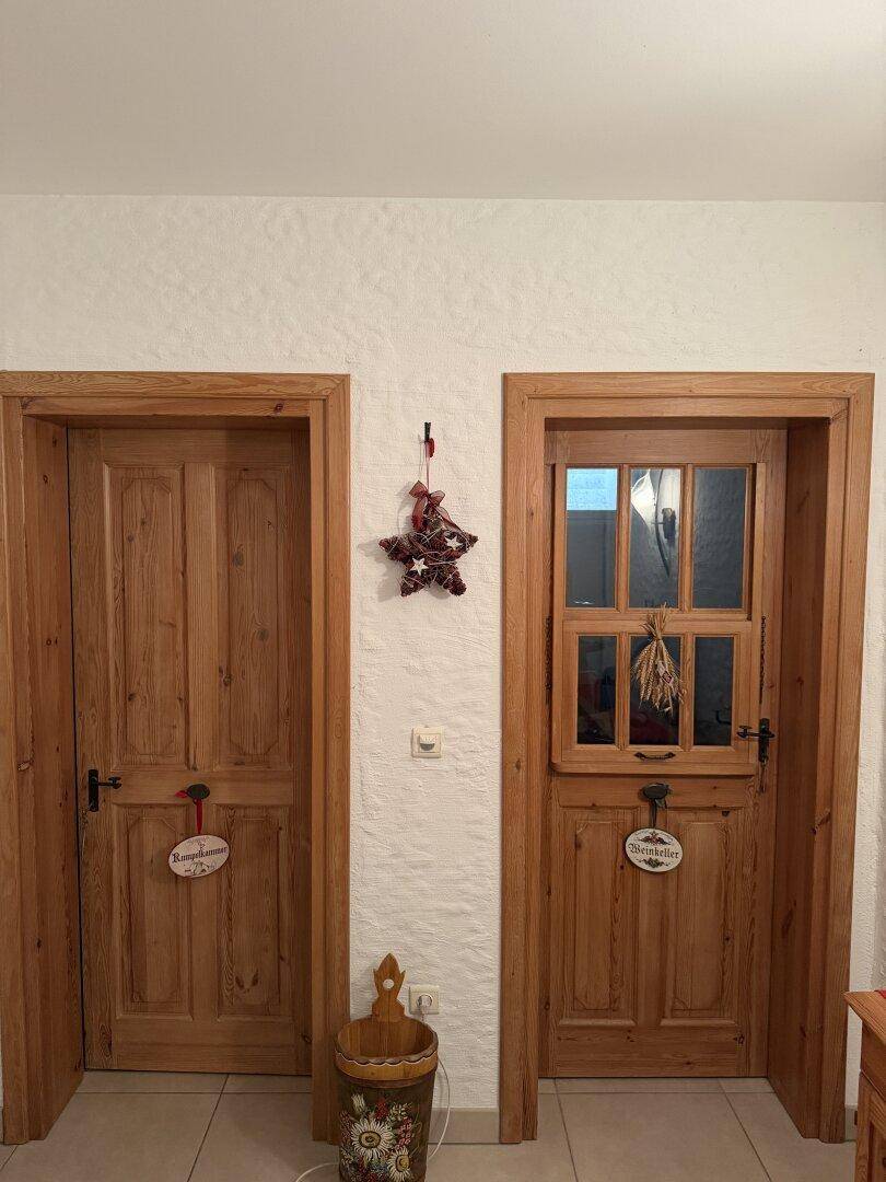 Zwei rustikale Holztüren im Flur, eine führt zum Weinkeller, die andere zu einem Raum.