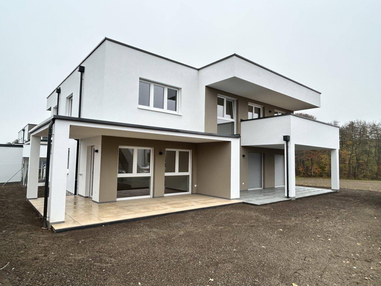 Modernes Einfamilienhaus mit klarer Architektur, großen Fenstern und einer überdachten Terrasse.