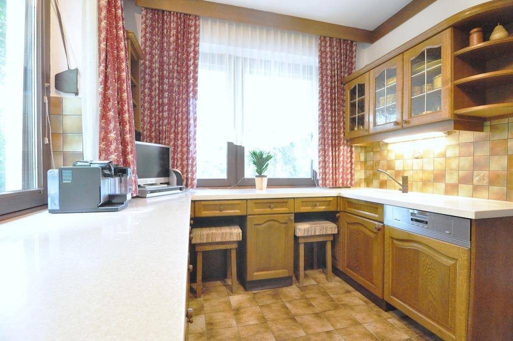 Gemütliche Küche mit Holzschränken, Frühstücksbar und einem großen Fenster für viel Tageslicht.