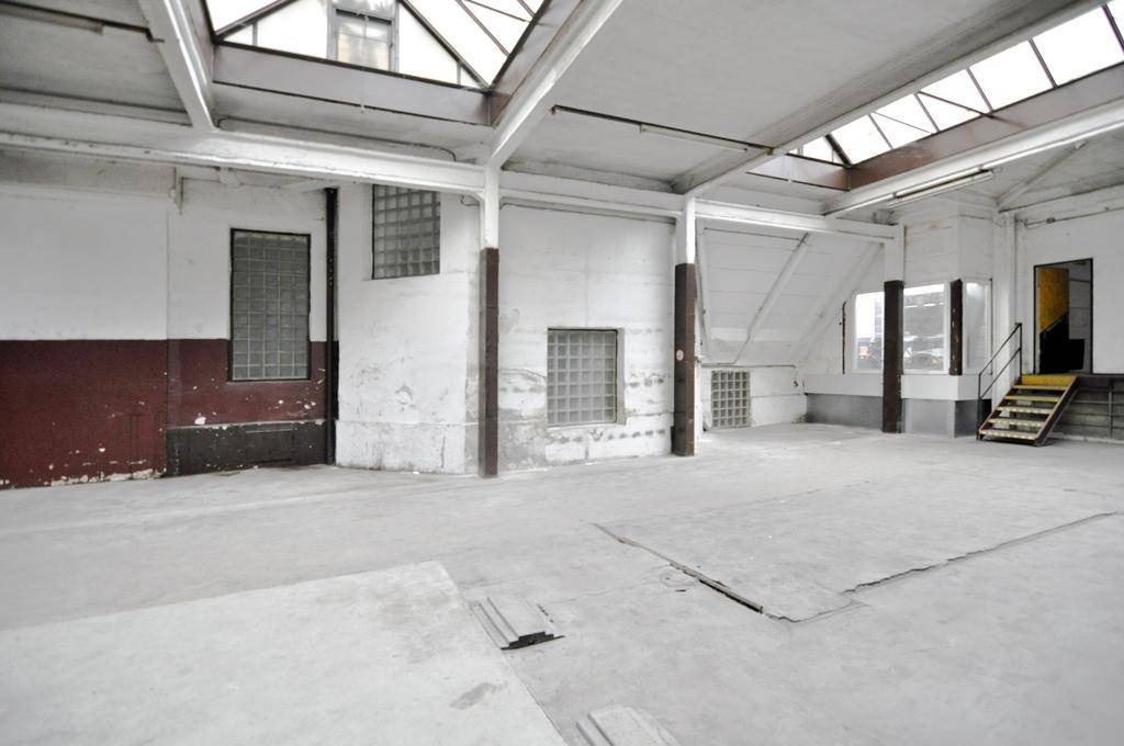 Weitläufiger Industrieraum mit Oberlichtern, Betonboden und sichtbaren Trägern, der auf eine Neugestaltung wartet.