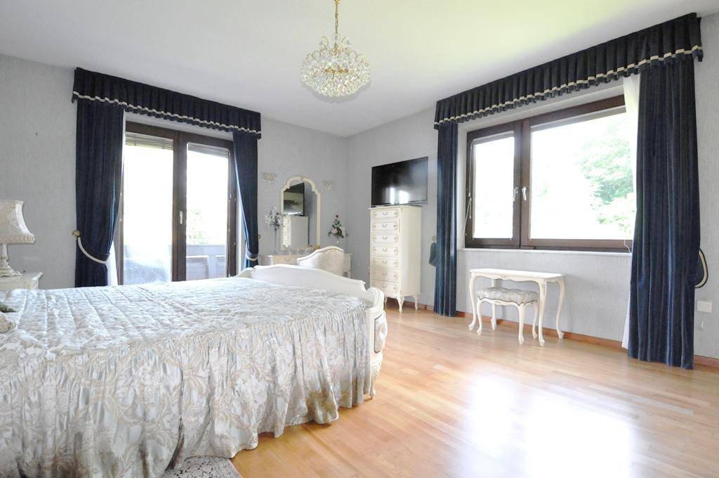 Helles Schlafzimmer mit großem Bett, Parkettboden und direktem Zugang zum Balkon.