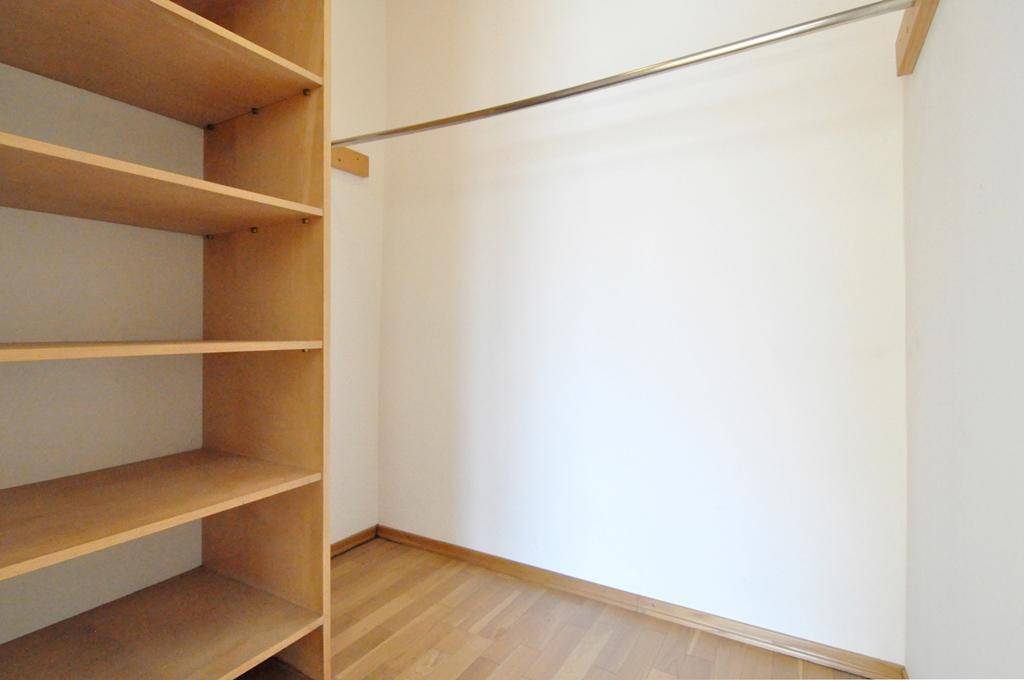 Praktischer Abstellraum mit Holzregalen und einer Kleiderstange für zusätzlichen Stauraum.