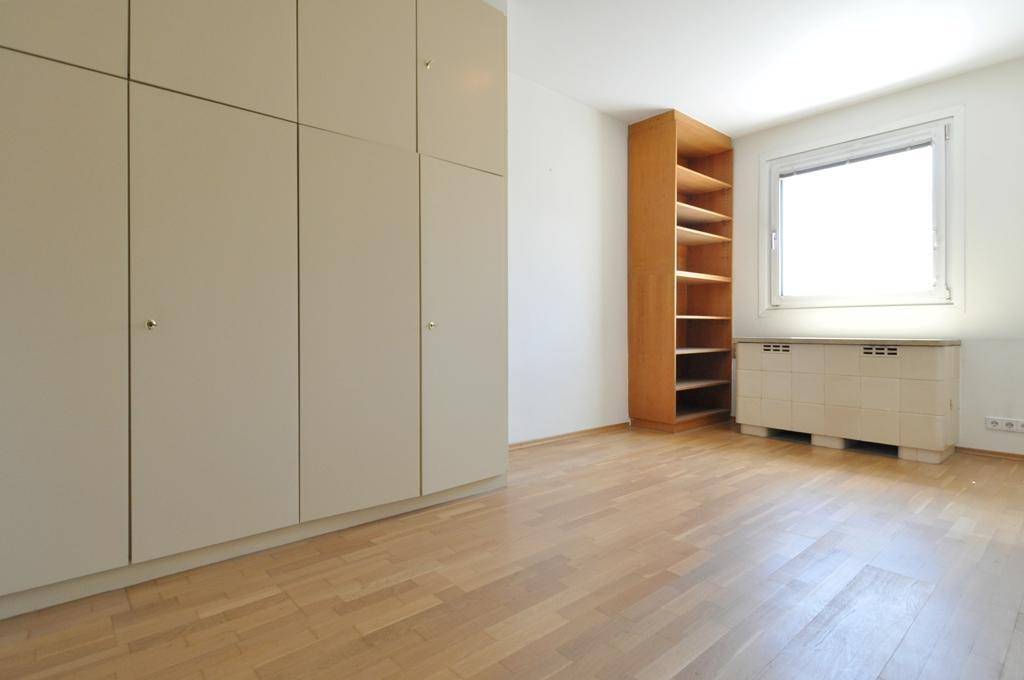 Geräumiges Zimmer mit Einbauschränken, Holzregal und hellem Parkettboden.