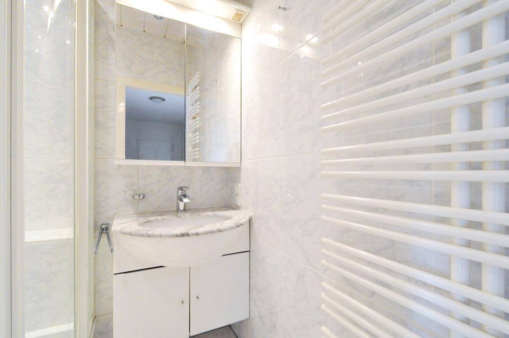 Helles Badezimmer mit Marmorwaschbecken, Spiegelschrank und beheiztem Handtuchhalter.