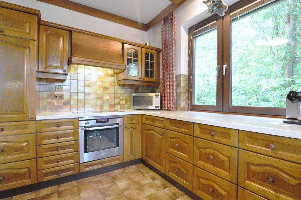 Traditionelle Holzküche mit integrierten Geräten und einem Fenster mit Blick ins Grüne.