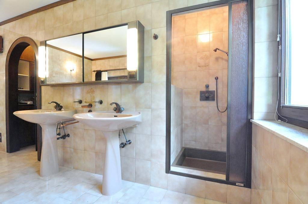 Funktionales Badezimmer mit Doppelwaschbecken, Spiegelschrank und einer Duschkabine.