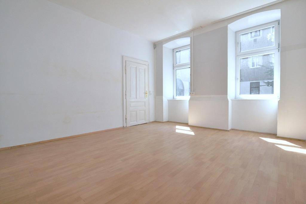 Leerer Raum mit hellem Holzboden, weiß gestrichenen Wänden und einer klassischen Tür.