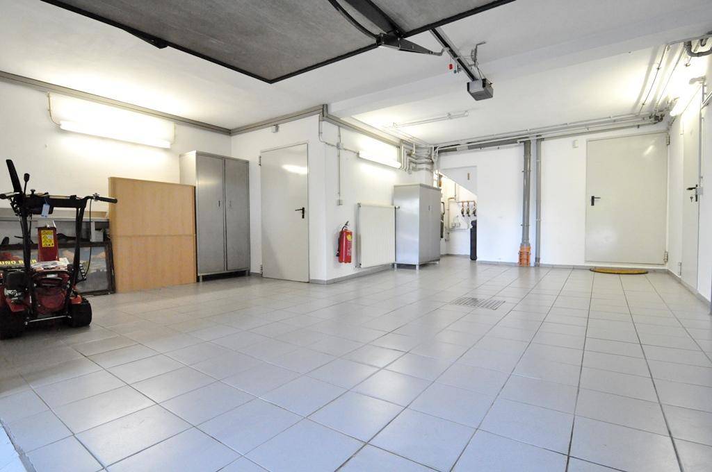 Große, helle Garage mit Fliesenboden, mehreren Türen und viel Stauraum.