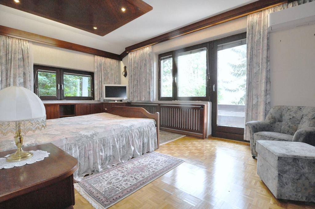 Geräumiges Schlafzimmer mit Holzboden, bequemen Möbeln und Zugang zu einem Außenbereich.