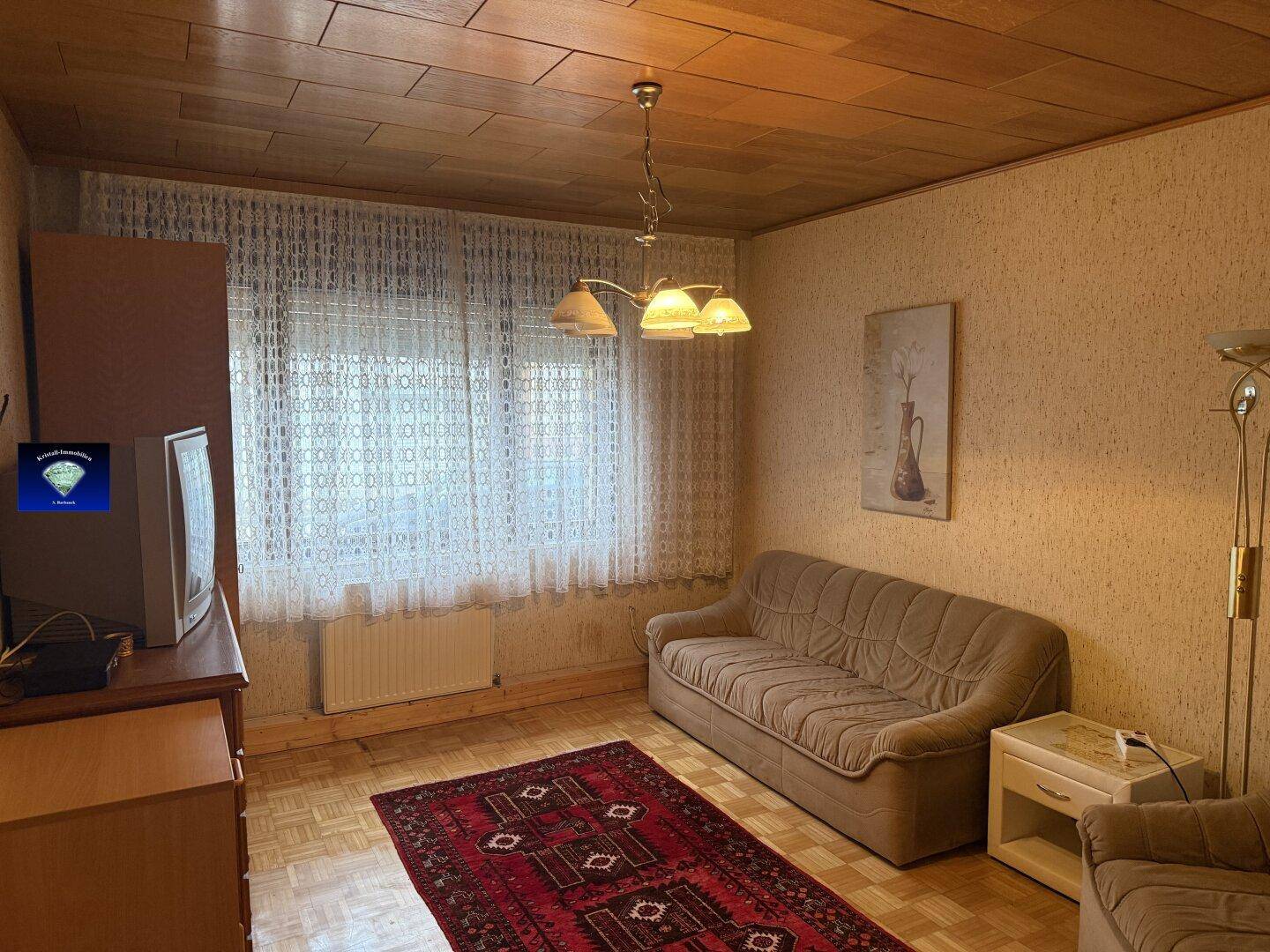 Wohnzimmer mit gemütlichem Sofa, Teppich und Holzdecke.