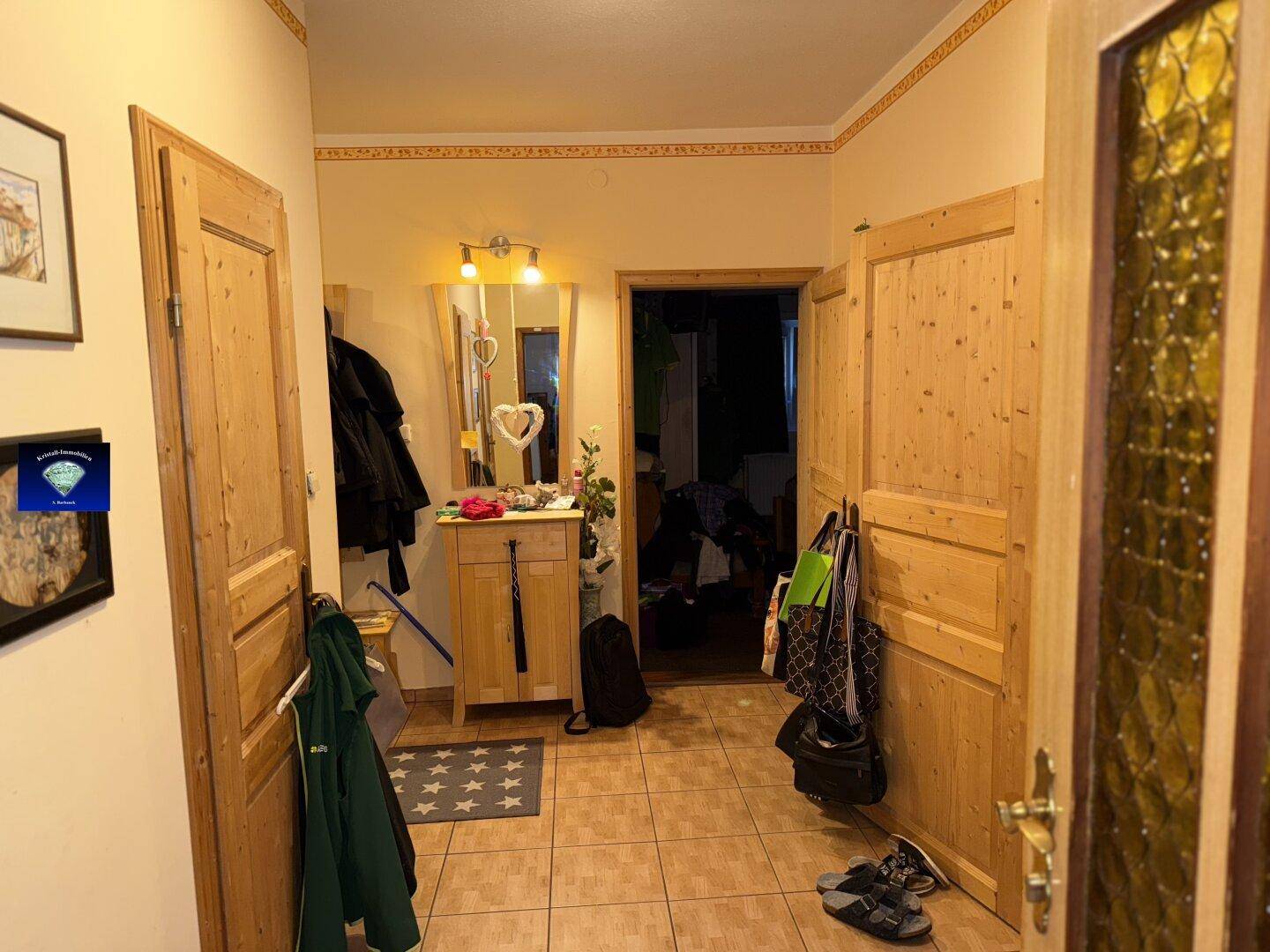 Eingangsbereich mit Fliesenboden, Holzmöbeln und Garderobe.