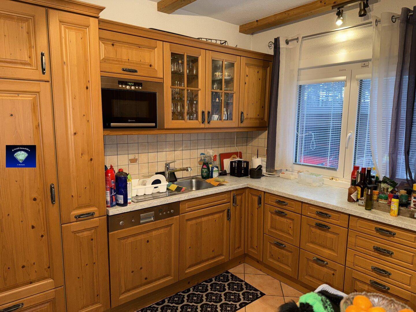 Traditionelle Holzküche mit Einbauschränken, Spülmaschine und Fenster.