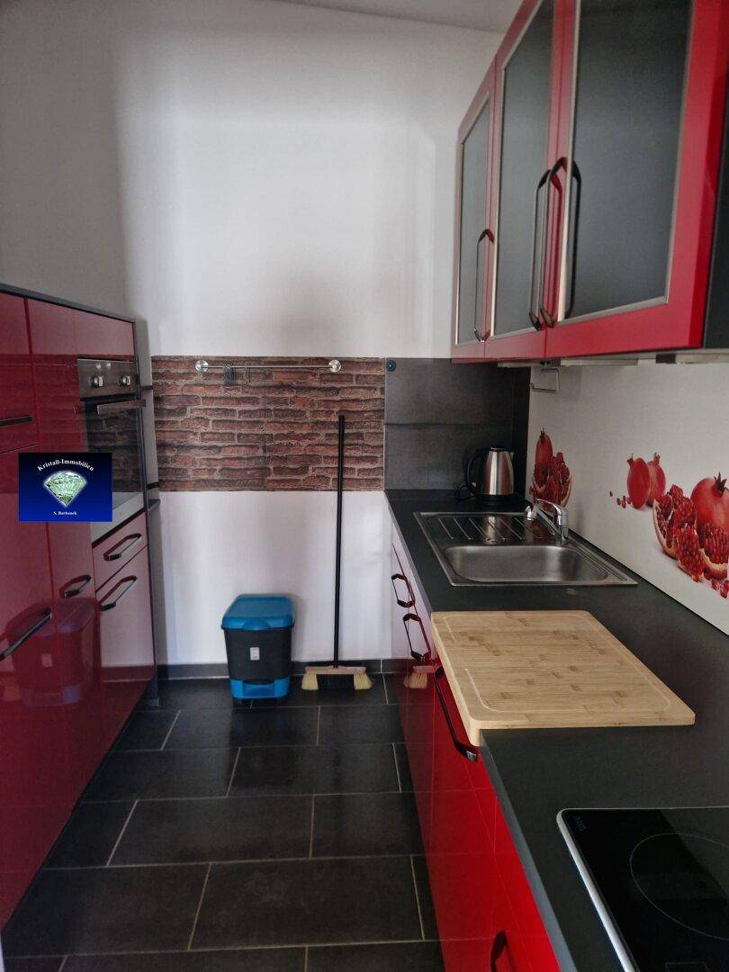 Moderne Küche mit roten Hochglanzfronten, dunklen Fliesen und Backsteinoptik-Rückwand.