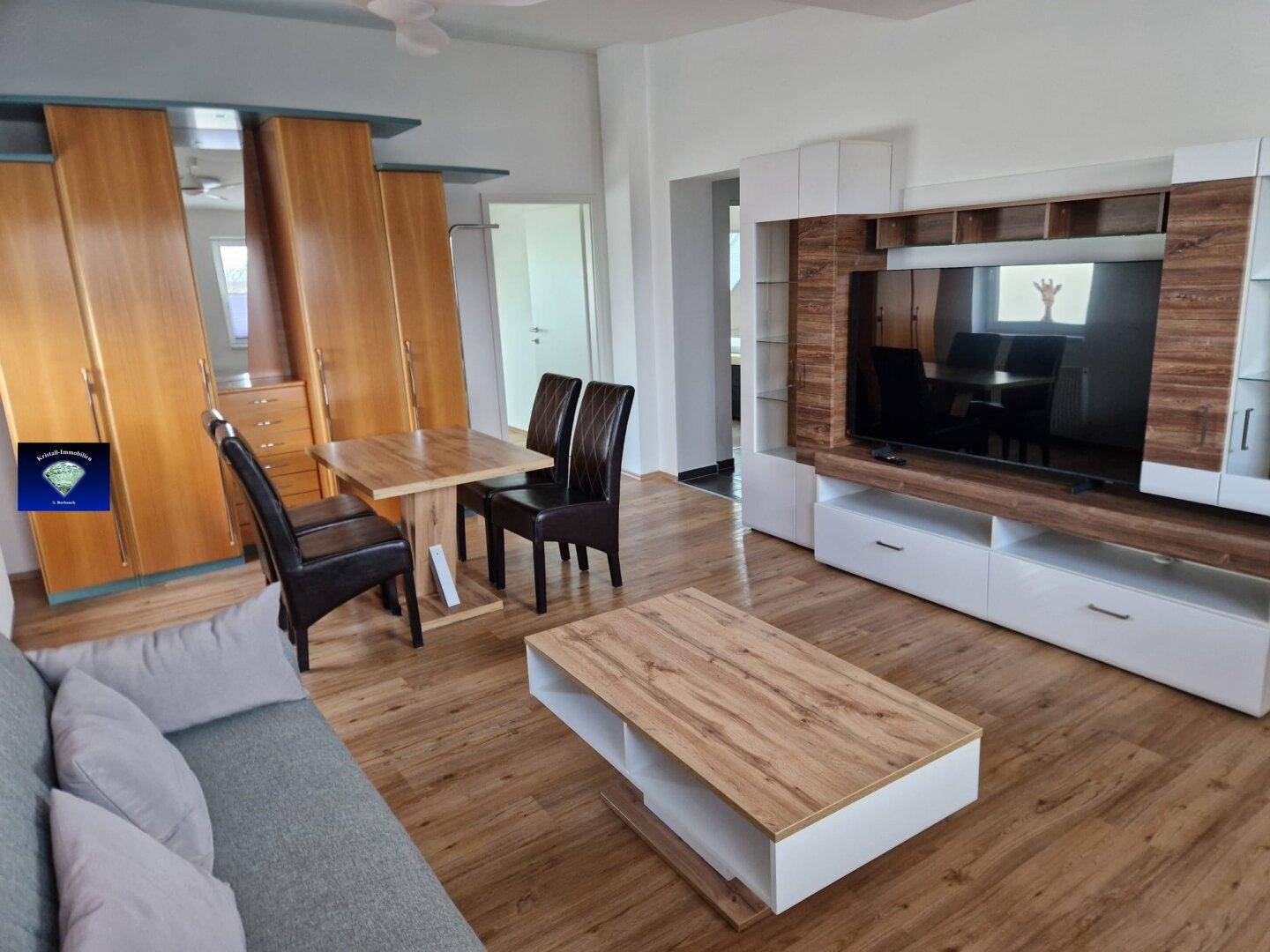 Heller Wohnbereich mit Sofa, Couchtisch, TV-Möbel und Deckenventilator.