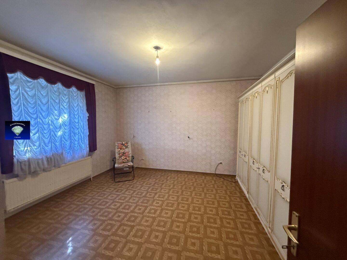 Geräumiges Schlafzimmer mit großem Kleiderschrank, Fenster und gemustertem Boden.