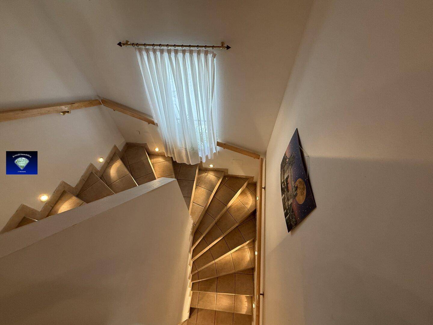 Geschwungene Treppe mit Fliesenstufen und einem Fenster, das den Bereich erhellt.