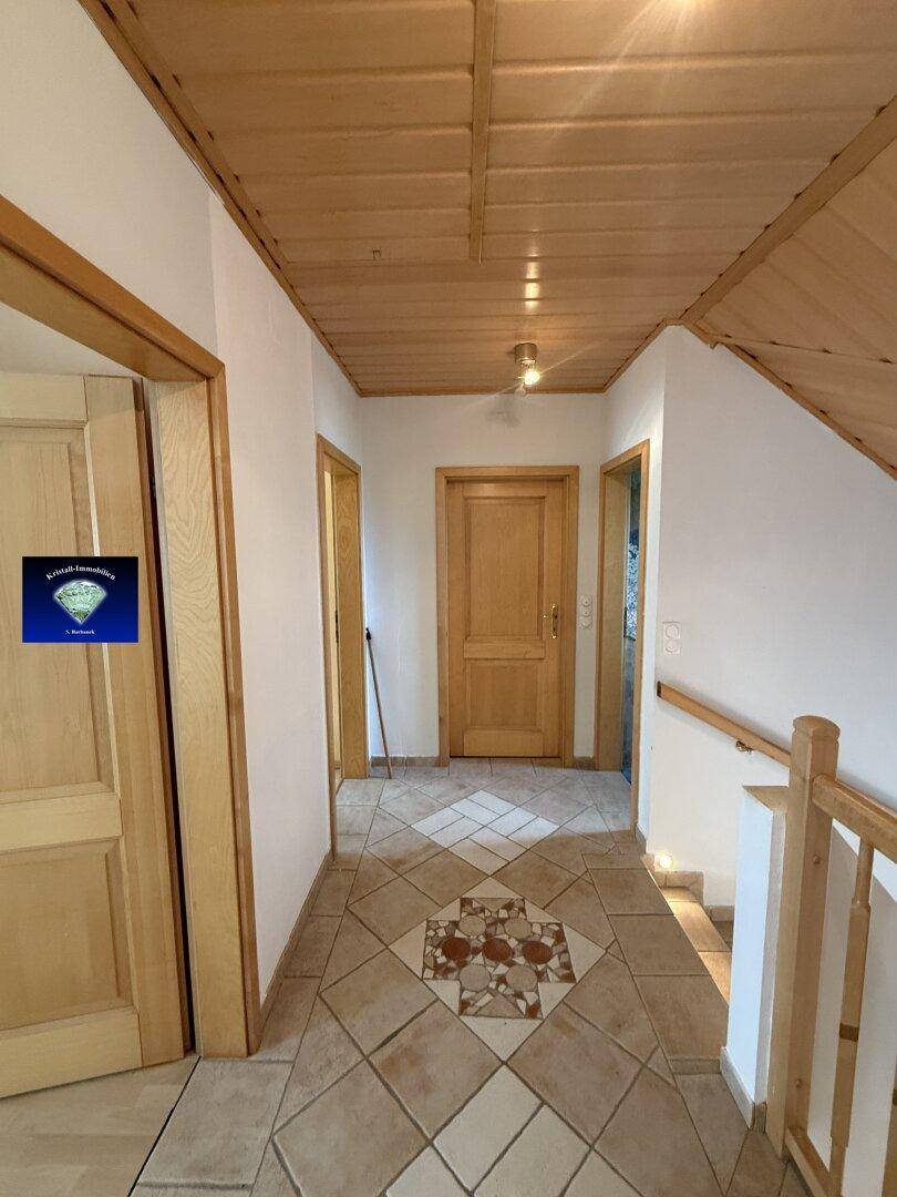 Flur mit Holztüren, Holzdecke und gemustertem Fliesenboden, der zu den Zimmern führt.