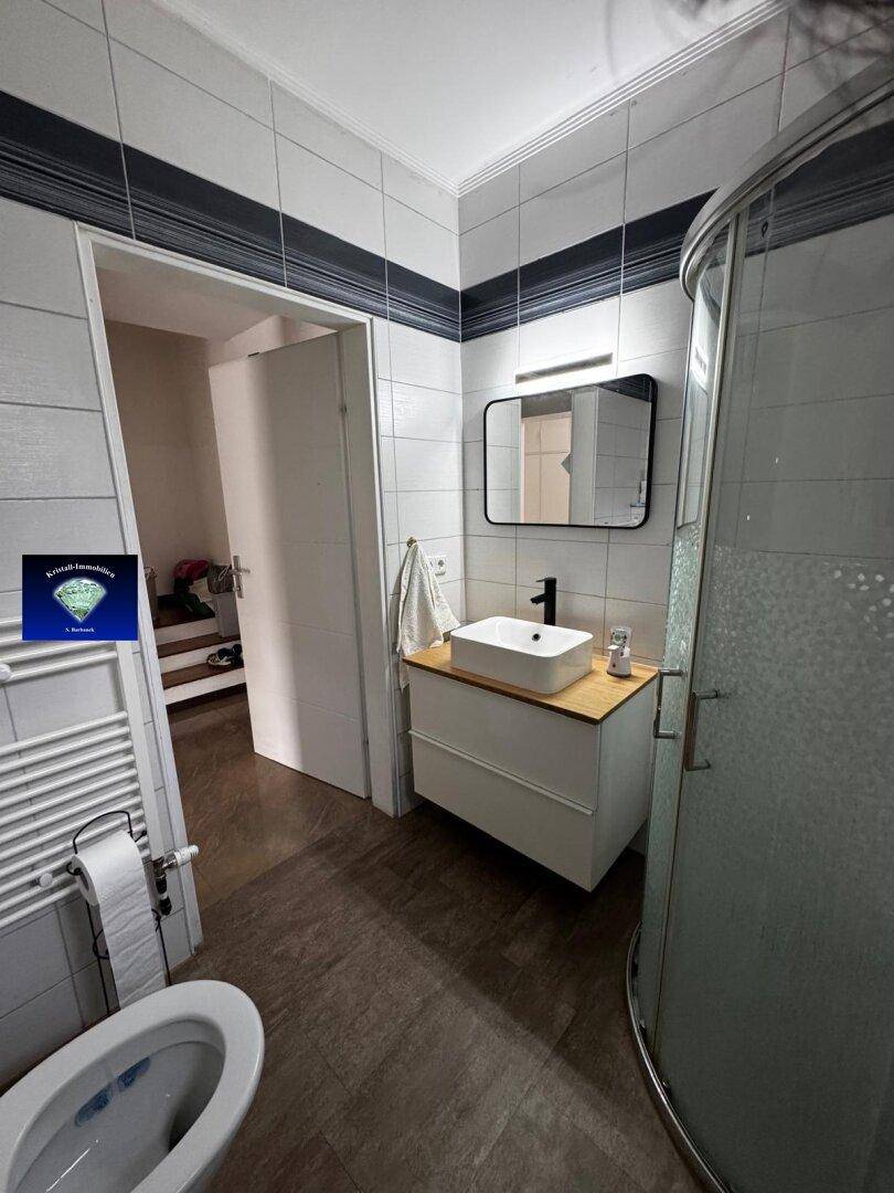 Modernisiertes Badezimmer mit Duschkabine, stilvollem Waschbecken und Spiegel über dem Waschtisch.