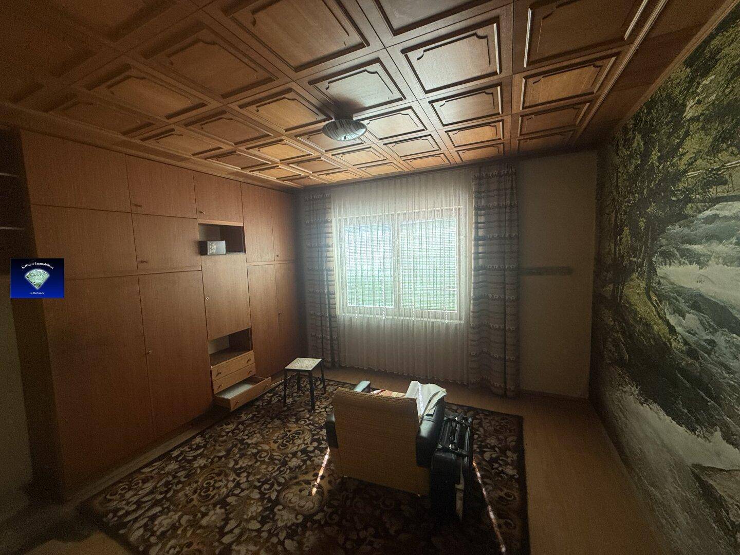 Schlafzimmer mit holzgetäfelter Kassettendecke, Einbauschränken und Teppichboden.