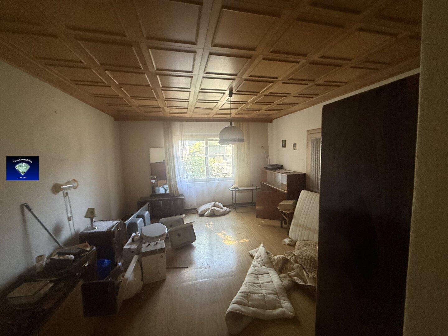 Geräumiges Zimmer mit Holzkassettendecke und Parkettboden, derzeit unmöbliert.