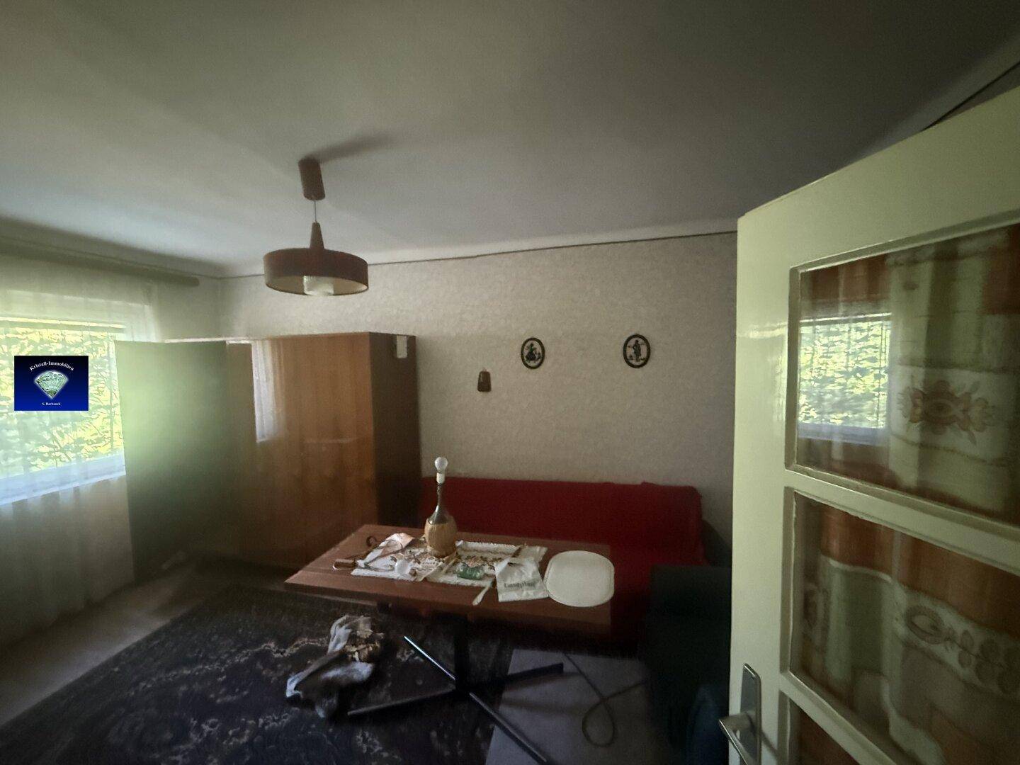 Wohnzimmer mit rotem Sofa, Esstisch und Fenster, dekoriert mit maritimen Elementen.