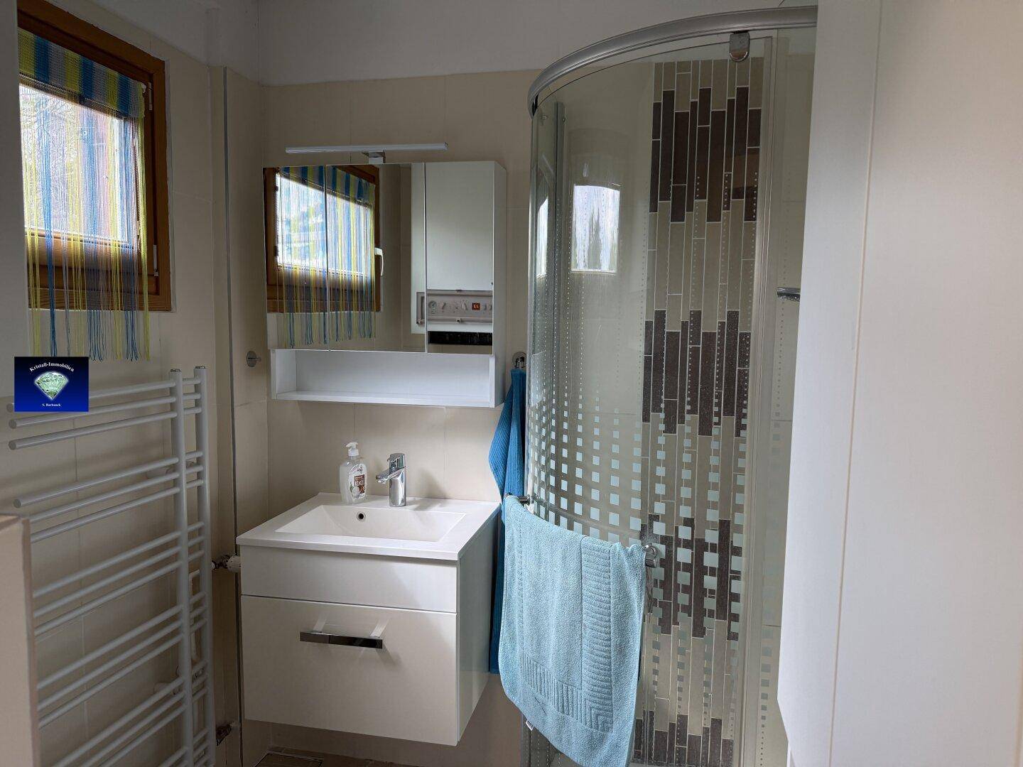 Modernes Badezimmer mit Duschkabine, Einzelwaschbecken und beheiztem Handtuchhalter.