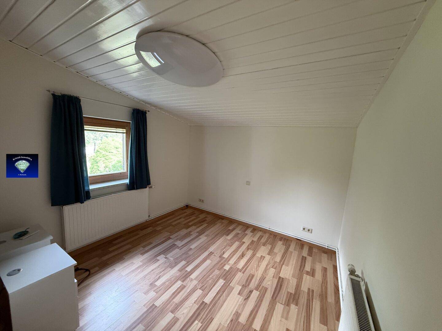 Helles Schlafzimmer mit Laminatboden, Fenster und Heizkörper, bereit zur individuellen Gestaltung.