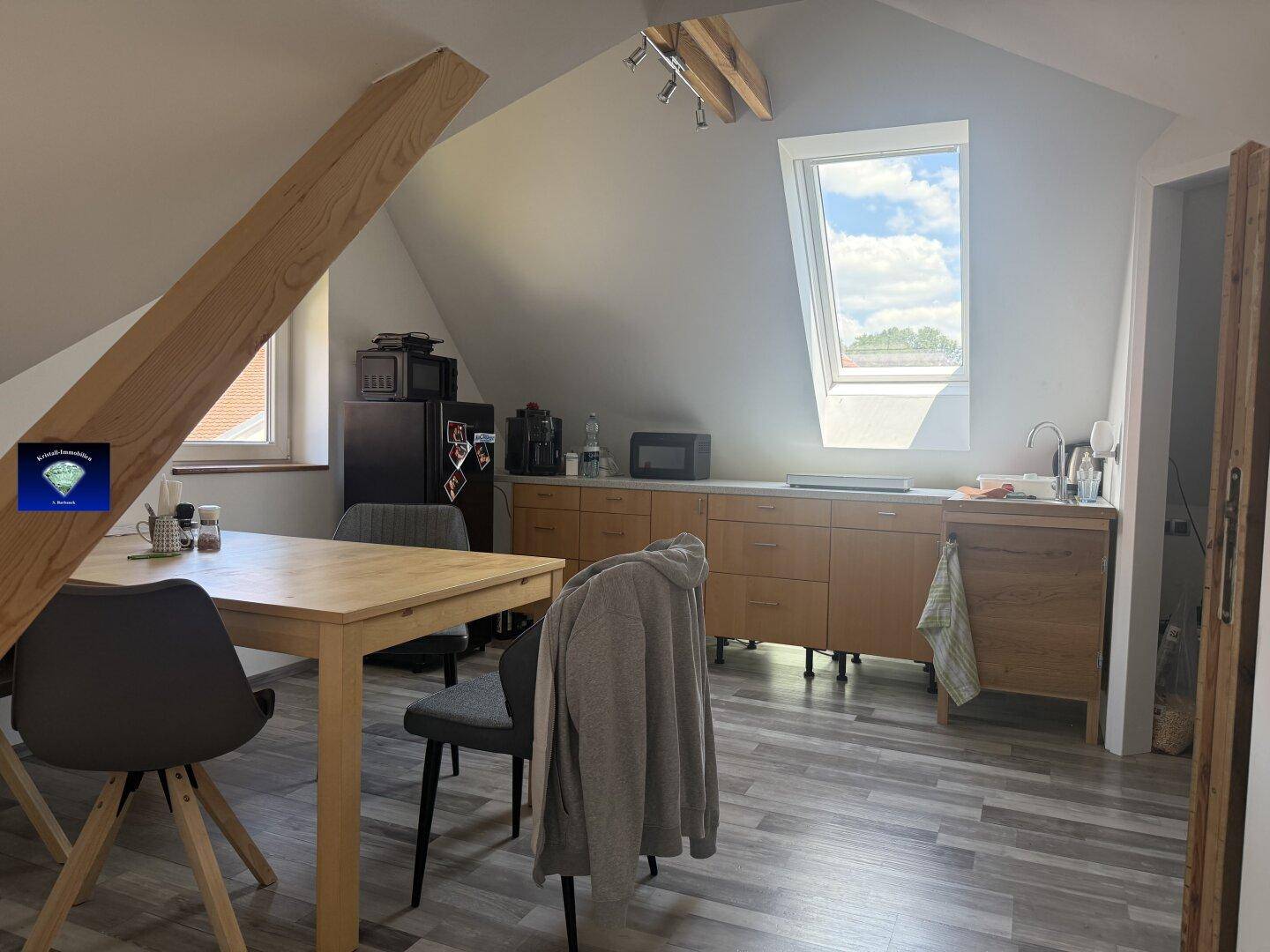 Offene Küche im Dachgeschoss mit Holzelementen, Esstisch und Dachfenster, ideal für modernes Wohnen.