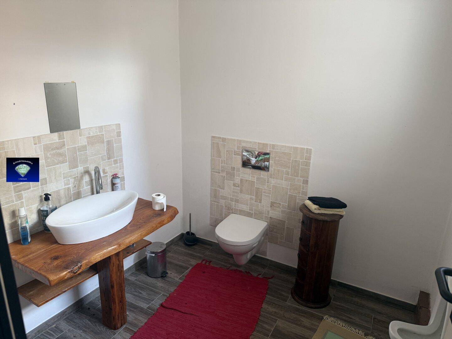 Modernisiertes Gäste-WC mit einem stilvollen Waschbecken auf einer Holzplatte und Wand-WC.
