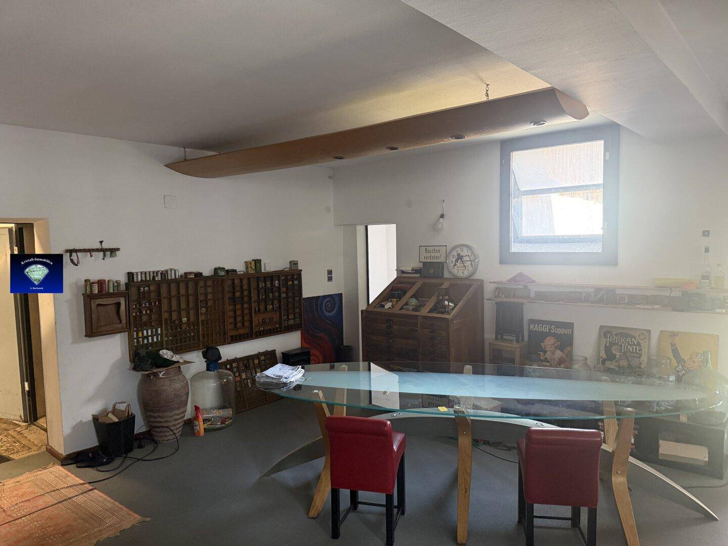 Großer Wohnbereich mit einem Glastisch, roten Stühlen und dekorativen Holzelementen an der Decke.
