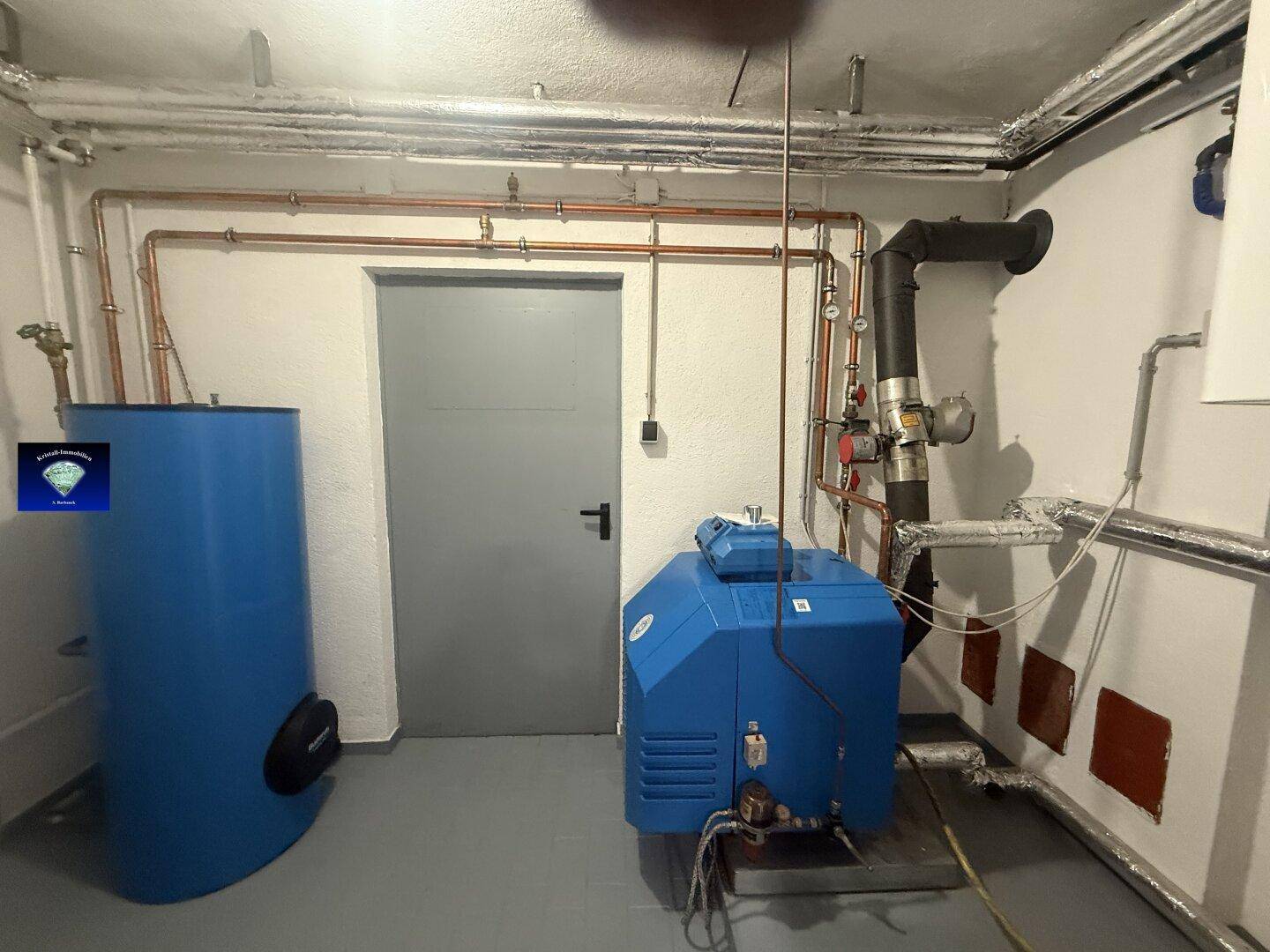 Heizungsraum mit Öltank und Heizkessel, alle Installationen sind sichtbar.
