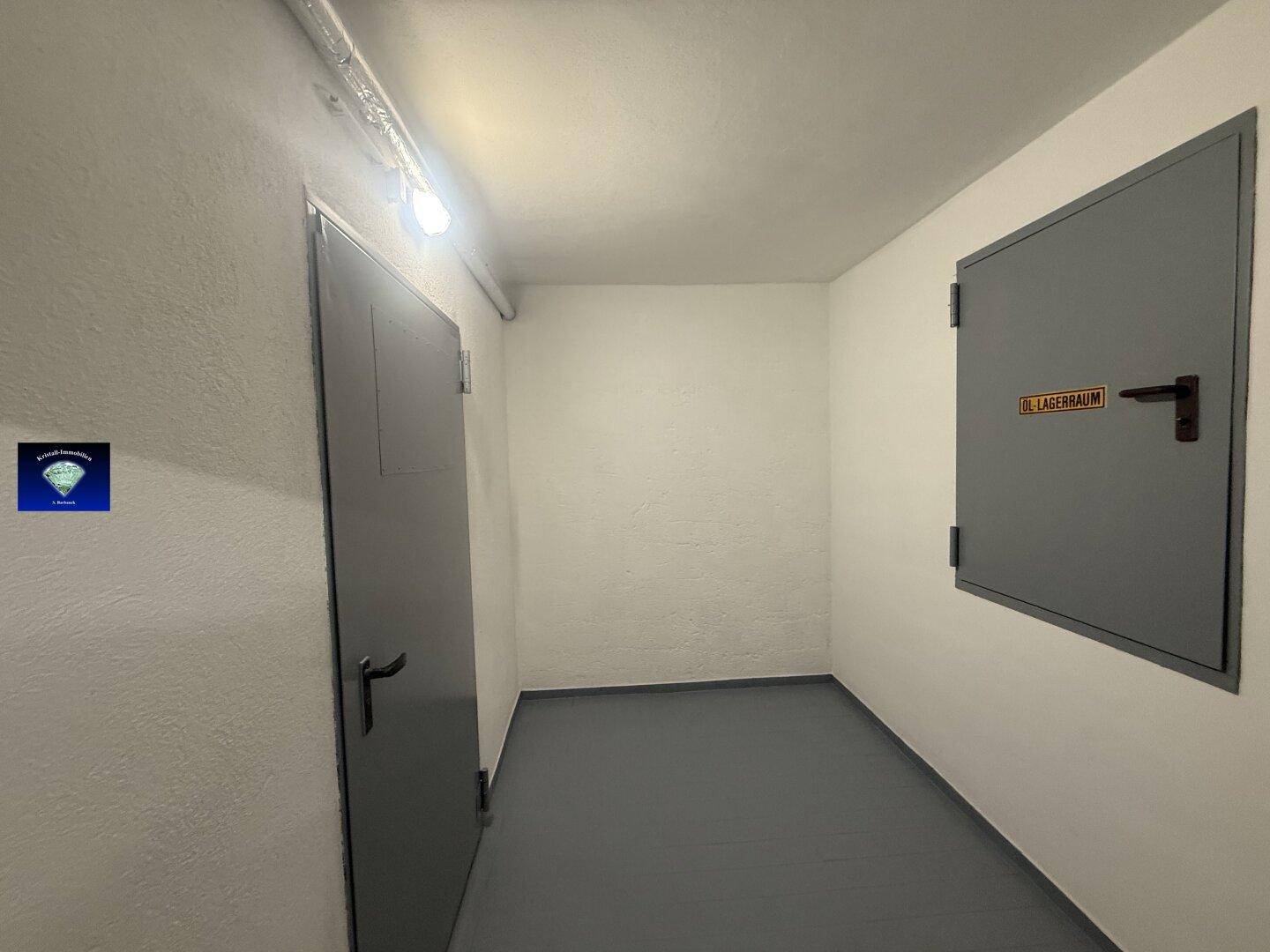 Kellerflur mit zwei Türen, darunter ein Öllagerraum, und robustem Boden.