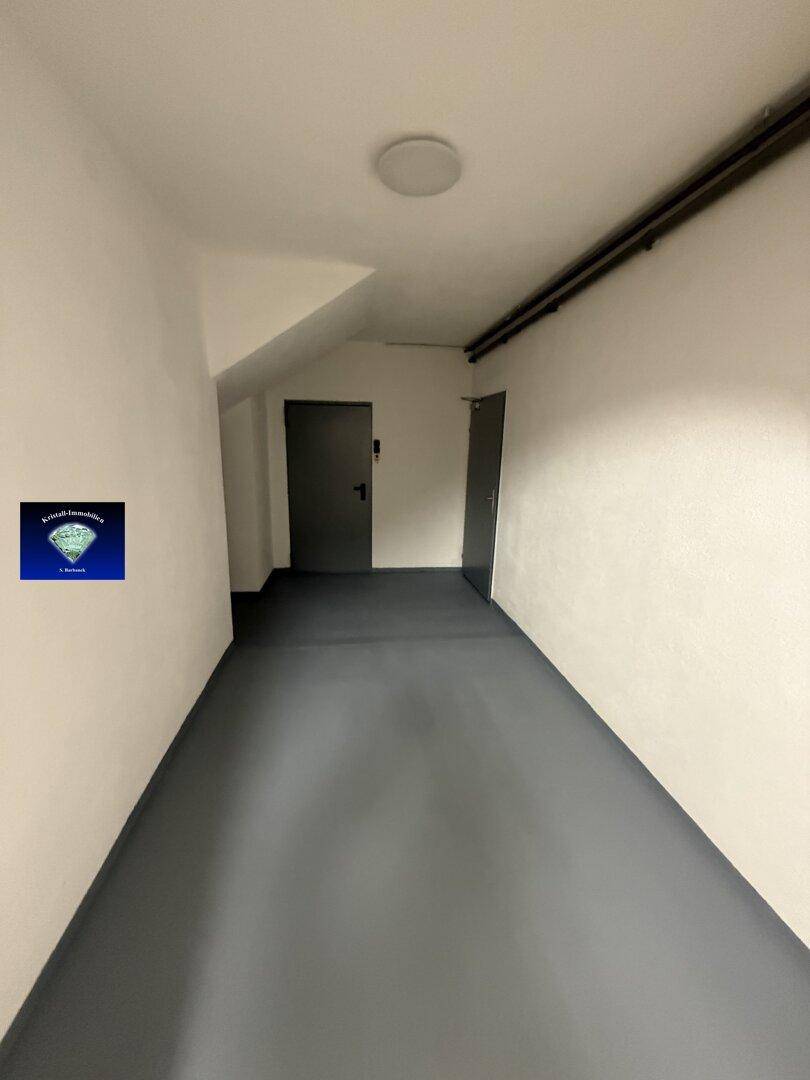 Langer Kellerflur mit Zugang zu verschiedenen Räumen und der Garage.