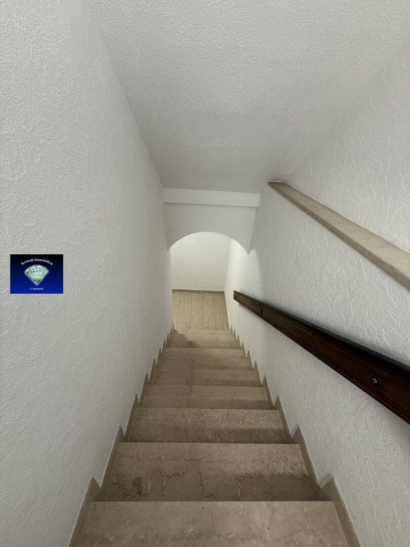 Marmortreppe mit Holzgeländer führt in den unteren Bereich des Hauses.