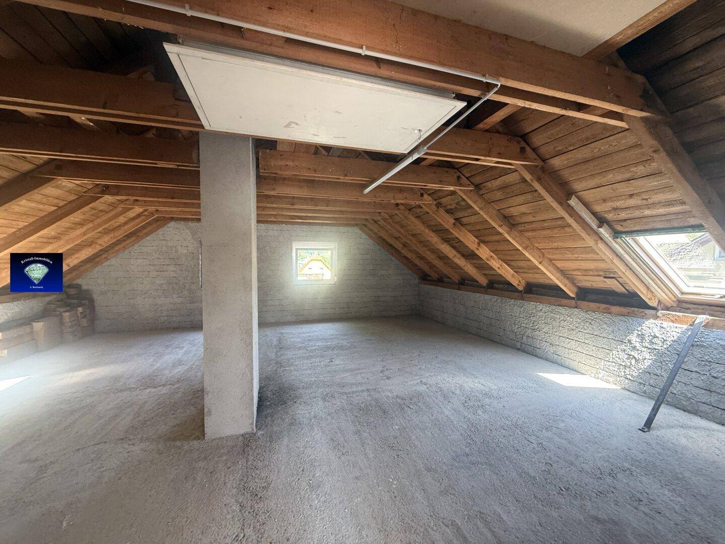 Unausgebautes Dachgeschoss mit sichtbaren Holzbalken und Dachfenstern, viel Stauraum.