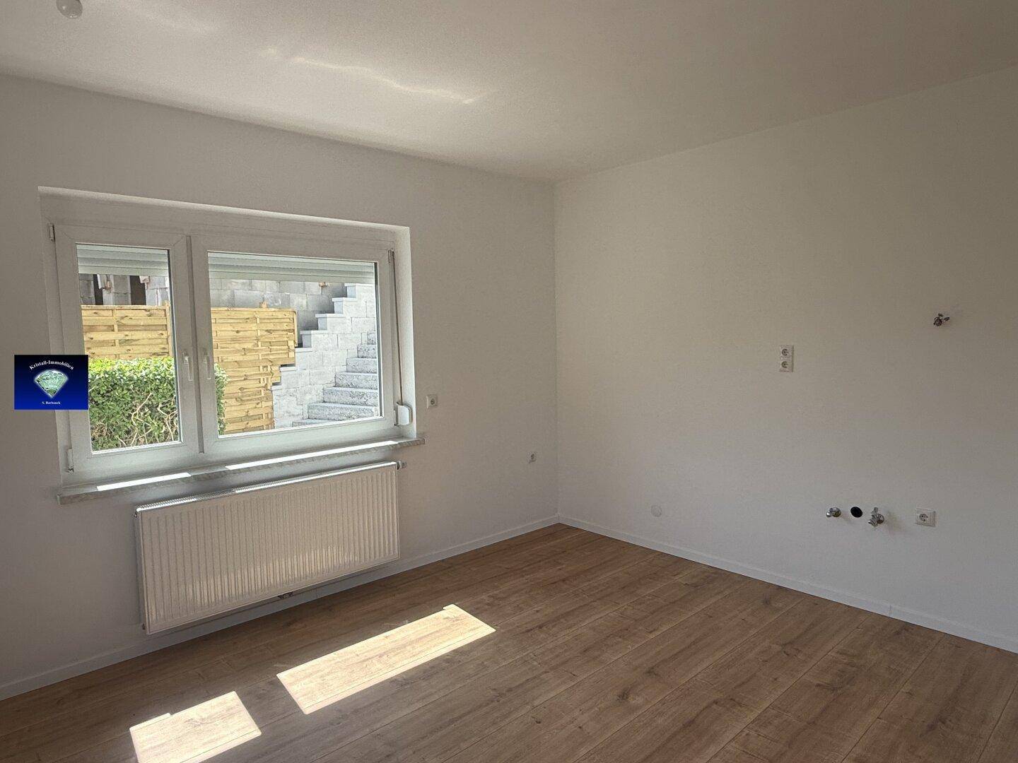 Zimmer mit Laminatboden und Fenster, das den Blick auf die Außentreppe freigibt.