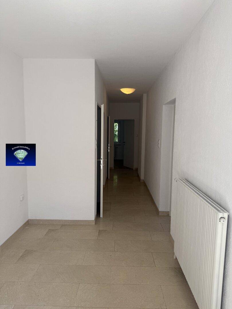 Geräumiger Flur mit Fliesenboden und Heizkörper, bietet Zugang zu weiteren Räumen.